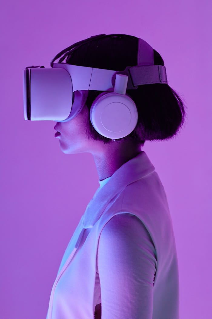 our-services-3 Side profile of a woman wearing VR goggles in a studio with purple lighting, embodying future tech.